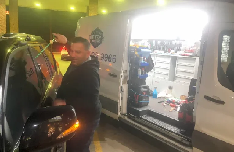 Mobile locksmith performing a nighttime car lockout in Prosper, TX, with the Meyer’s Local Locksmith van open and tools visible.